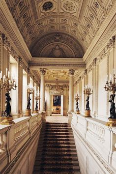 an ornate hallway with chandeliers and marble steps leading up to the second floor