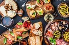 an assortment of food on wooden platters with wine and breads in the background