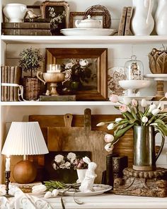 a shelf filled with vases and other items on top of a white mantle covered in books