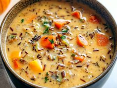 a close up of a bowl of soup with carrots and other foods in it