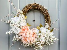 a wreath with flowers hanging on the front door