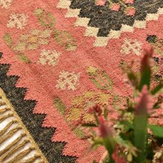 a close up of a rug with flowers on the ground and plants in the foreground