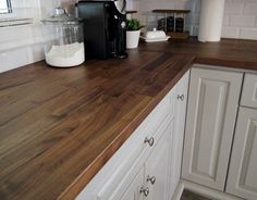 a kitchen counter top with white cabinets and wood