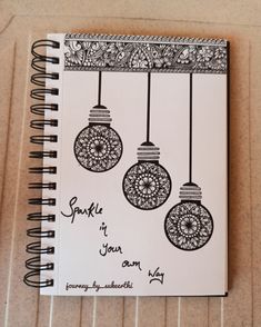 a spiral notebook with three ornaments hanging from it's sides and the words sparkle in your own language