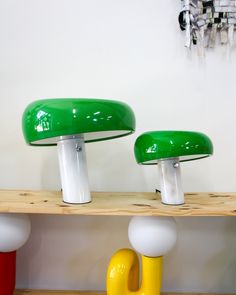 two green and white mushrooms sitting on top of a wooden shelf next to each other