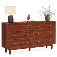 a wooden dresser with two vases on top and a lamp next to the drawers