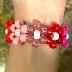 a woman's wrist with pink, red and white bracelets