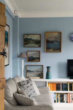 a living room with bookshelves and pictures on the wall above it's couch