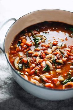 a pot filled with beans and spinach on top of a table