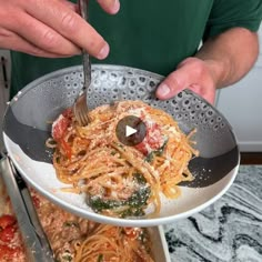 a person holding a plate with spaghetti and sauce