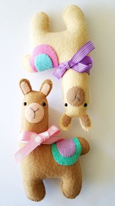 two llamas are holding each other on a white background with pink and green ribbons