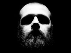 black and white photograph of a bearded man's face in the dark with his eyes closed