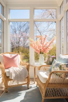 two wicker chairs in front of large windows with pink and white flowers on them