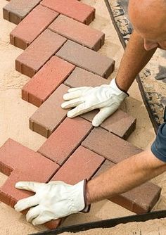 a man laying bricks on top of a floor next to a fire hydrant with his hands in the ground