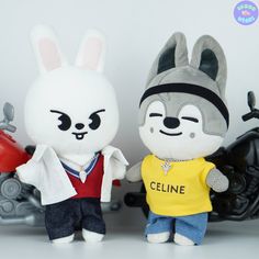 two stuffed animals standing next to each other on a white surface with motorcycles in the background