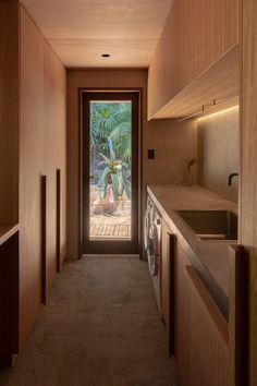 a long narrow hallway leading to a kitchen with wooden cabinets and counter tops on both sides