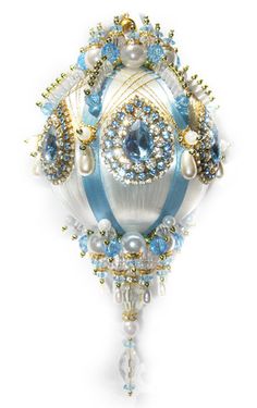 a brooch with blue and white beading on it's side, hanging from a wall