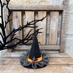 a black and orange hat sitting on top of a wooden bench next to a tree