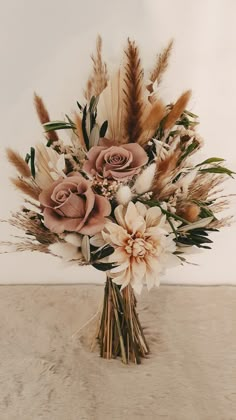 a vase filled with lots of flowers on top of a table next to a wall