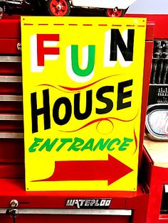 a sign that says fun house entrance on the front of a red truck with an arrow pointing to it