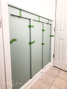 some green tape is taped to the wall in front of a white door and tile floor