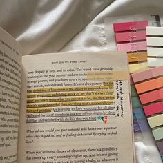 an open book sitting on top of a bed next to colorful magnets and paper clips