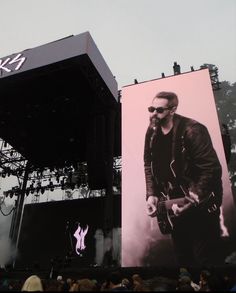 a large billboard with a man playing guitar in front of an audience at a concert