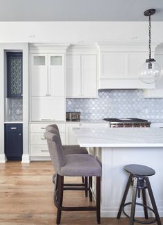 a kitchen with two stools in front of an island and white cabinetry,