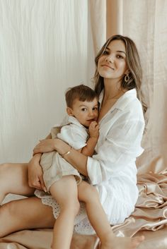 a woman holding a small child on top of a bed