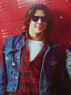 a man wearing sunglasses standing in front of a red locker with his hands on his hips