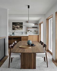 a dining room table with chairs and a bowl on top of it in front of an open kitchen