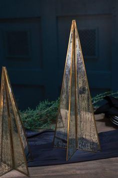 three metal sculptures sitting on top of a wooden floor next to a blue door and green plant