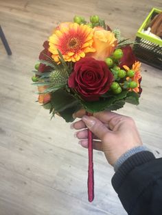 a person holding a bouquet of flowers in their hand on a wooden flooring surface