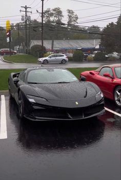 two sports cars parked in a parking lot next to each other on a rainy day