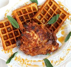 some waffles are sitting on a plate with syrup and leaves around them,