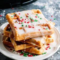 a stack of waffles topped with white frosting and sprinkles