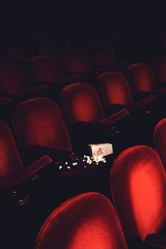 an empty theater with red chairs and popcorn