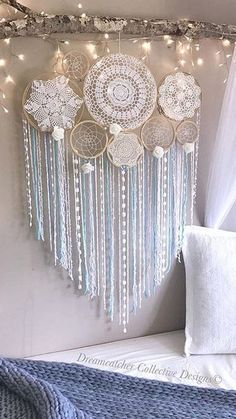 a wall hanging decoration with white doily and lights on the ceiling, in front of a window