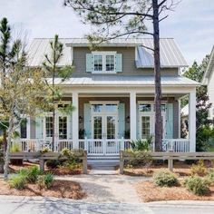 a gray house with white trim on the front porch and two story entryway leading up to it