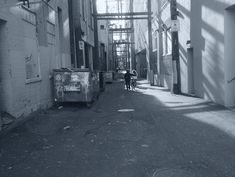 a person walking down an alley way in black and white