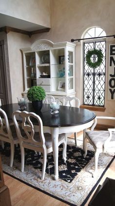 a dining room table with white chairs and a rug on the floor in front of it