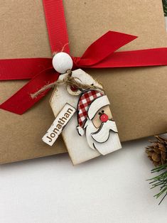 a christmas ornament hanging from the side of a brown box with a red ribbon