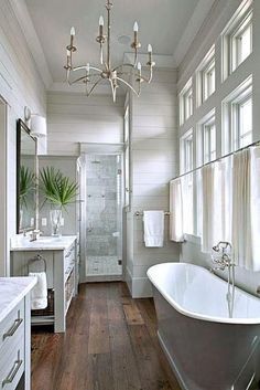 a bathroom with a claw foot bathtub and wooden floors, along with a chandelier that hangs from the ceiling