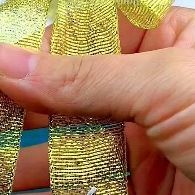 a person is holding some gold colored bracelets in their hand and they are all covered with sequins