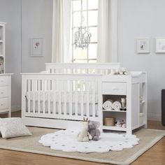 a white crib with a teddy bear and stuffed animal on the floor next to it