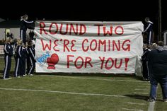 a group of people standing on top of a field holding a banner