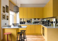 a kitchen with yellow cabinets and stools