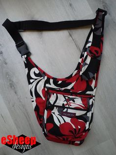 a red and black floral print purse on a white wooden floor with the strap down