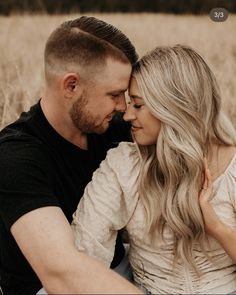 a man and woman are sitting together in the grass looking at each other with their eyes closed