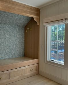 an empty room with some drawers and a window in the corner that has a blue wallpaper on it